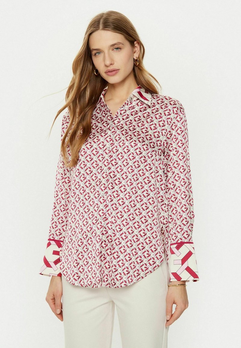 Camicia bianca con un motivo geometrico rosso, colletto a punta e polsini a contrasto con un design simile. Tessuto morbido, stile con bottoni.