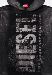 Haut à capuche noir avec un logo "DIESEL" en argent métallique et le texte "POUR UNE VIE RÉUSSIE". Il présente une finition texturée et une capuche avec cordon.