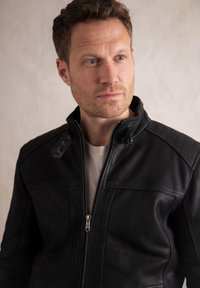 Men's black leather jacket with a high collar, zip closure, and accent stitching on shoulders; smooth texture and tailored fit.