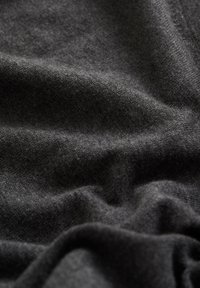 Dunkelgrauer Strickstoff mit einer weichen, glatten Textur, der subtile Variationen in Farbe und Tiefe aufweist, in sanften Falten drapiert.