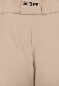 Beige housut, jotka on valmistettu sileästä, hieman teksturoidusta kankaasta. Vaatteessa on näkyvä musta "SLOPE"-logo vyötäröllä ja siisti ompelu.
