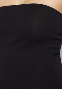 Top preto sem alças, feito de um tecido liso e elástico, apresentando um design ajustado com um decote reto e costuras mínimas.