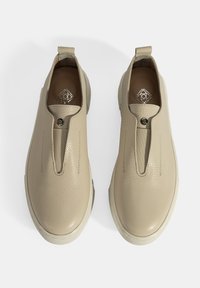 Beige leren instapschoenen met een gestructureerde afwerking, voorzien van een ronde neus, elastische zijkanten en een klein lusje aan de hiel.