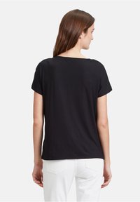 T-shirt nera a maniche corte realizzata in tessuto morbido, con un design semplice, scollatura rotonda e vestibilità rilassata, mostrata da dietro.