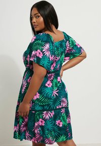 Vestido floral con base verde oscuro, decorado con flores rosas y patrones de hojas, mangas cortas y una cintura fruncida para un ajuste relajado.
