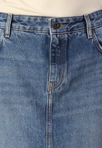 Denim krilo v svetlo modri barvi z rahlo teksturo, ravne oblike in sprednjim zapiranjem na gumb. Kontrastni šivi in žepi obogatijo obliko.