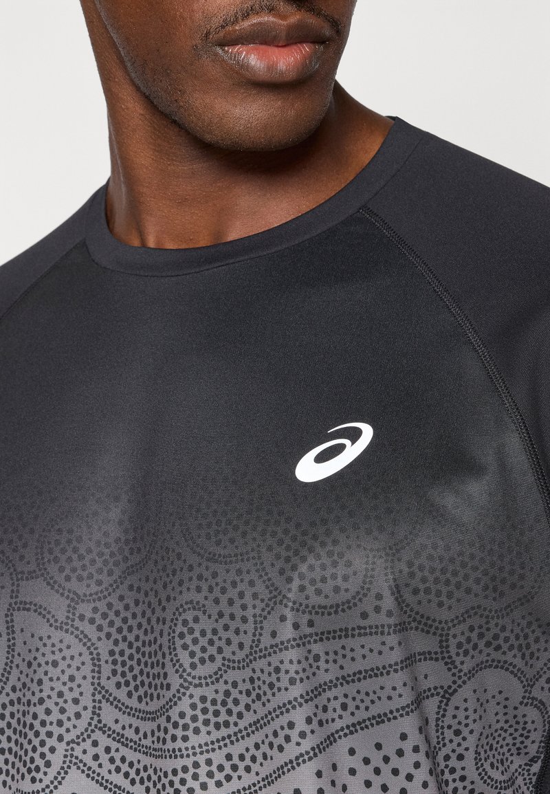 T-shirt de sport noir avec un design en dégradé et des motifs texturés, un col rond et un logo blanc sur la poitrine.