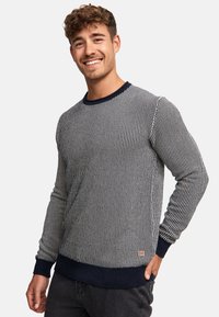 Gestreifter Strickpullover in Marineblau und Weiß mit langen Ärmeln, Rippenbündchen und -saum, ausgestattet mit einem kleinen Logo-Patch unten links.