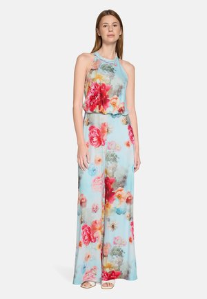 Combinaison florale en tissu bleu clair ornée de fleurs rouges, roses et pastel. Design sans manches avec une taille cintrée et un pantalon large fluide.