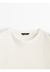 T-shirt blanc uni à col rond avec une étiquette de marque noire visible cousue à l'intérieur du col.