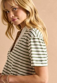 Valgest ja rohelisest triibuline puuvillane särk, millel on krae ning brändi nimi "JOULES" rohelise niidiga õmmelduna varrukal.