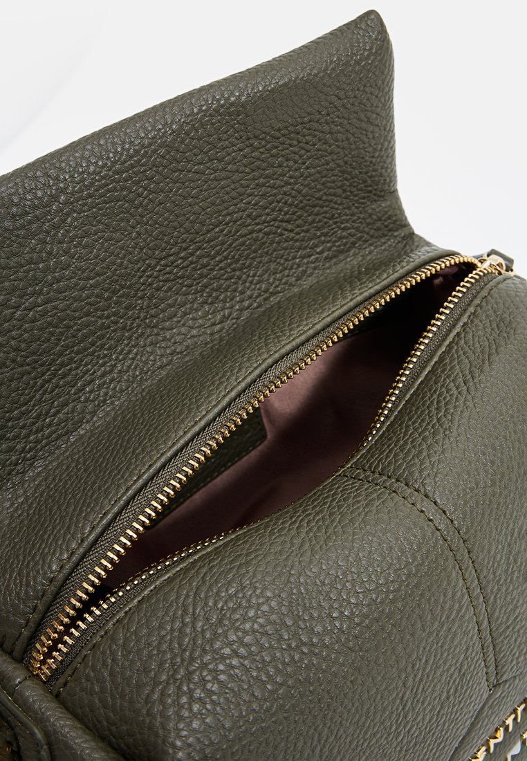 Sac à dos en cuir vert olive avec une surface texturée, rabat supérieur et détails de fermeture éclair dorés ; l'intérieur est doté d'une doublure douce et rose clair.