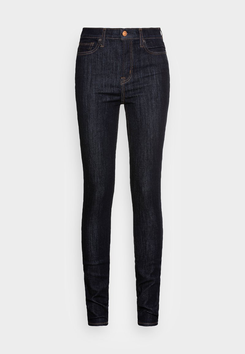 Jeans skinny de mezclilla azul oscuro con una cintura de talle medio, costuras sutiles y herrajes de cobre, que presentan una textura suave y una silueta ajustada.