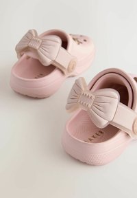 Roosa plastikust sabad, millel on tekstuuriga pind, paela kujulised aksessuaarid rihmal ja pehme, vormitud jalapadi.