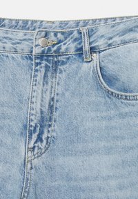 Svijetloplave traperice s izblijedjelim završetkom, sa srebrnim gumbom, petljama za remen i žutim šavovima duž džepova i šavova.