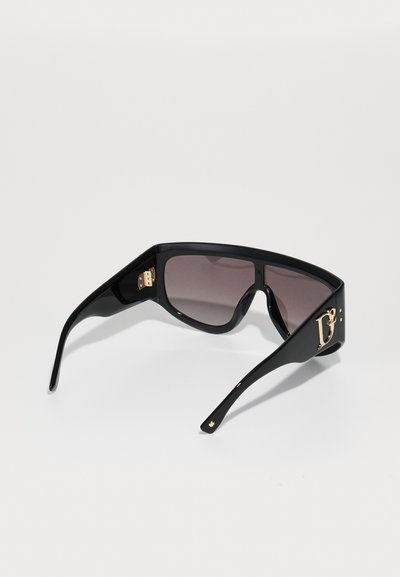 Black sunglasses with gradient lenses, bold angular design, gold hardware accents, and a distinct logo on the temple.