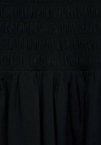 Abito nero caratterizzato da tessuto arricciato sulla parte superiore e un fondo fluttuante con volant. La trama è morbida con una tessitura uniforme in tutto l'abito.