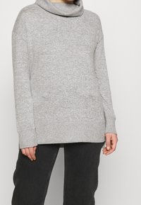 Grauer Pullover mit Kapuze, langen Ärmeln, gerippten Bündchen und lockerer Passform. Sanfte Textur mit einem subtilen gefleckten Muster.