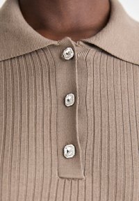 Brun stripete polo skjorte med klassisk krage og fire dekorative knapper med metallkanter. Glatt tekstur og tettsittende design.
