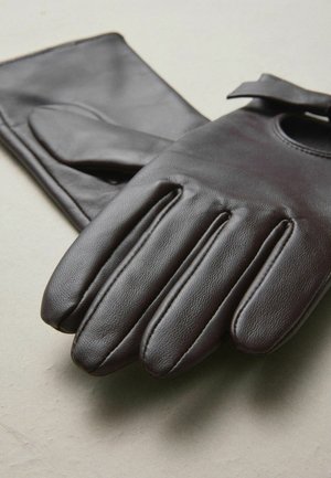 Brūnas ādas cimdi ar pieciem pirkstiem, gludu tekstūru, apaļu izgriezumu pie plaukstas locītavas un smalkām šūšanas detaļām.