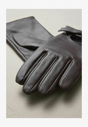 Brūnas ādas cimdi ar pieciem pirkstiem, gludu tekstūru, apaļu izgriezumu pie plaukstas locītavas un smalkām šūšanas detaļām.