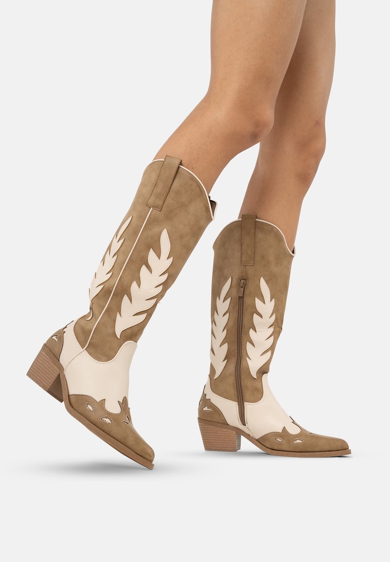 Brązowe zamszowe kowbojki z białymi skórzanymi akcentami, zdobione wzorami liści, z zamkiem błyskawicznym i piętą w kształcie stosu.