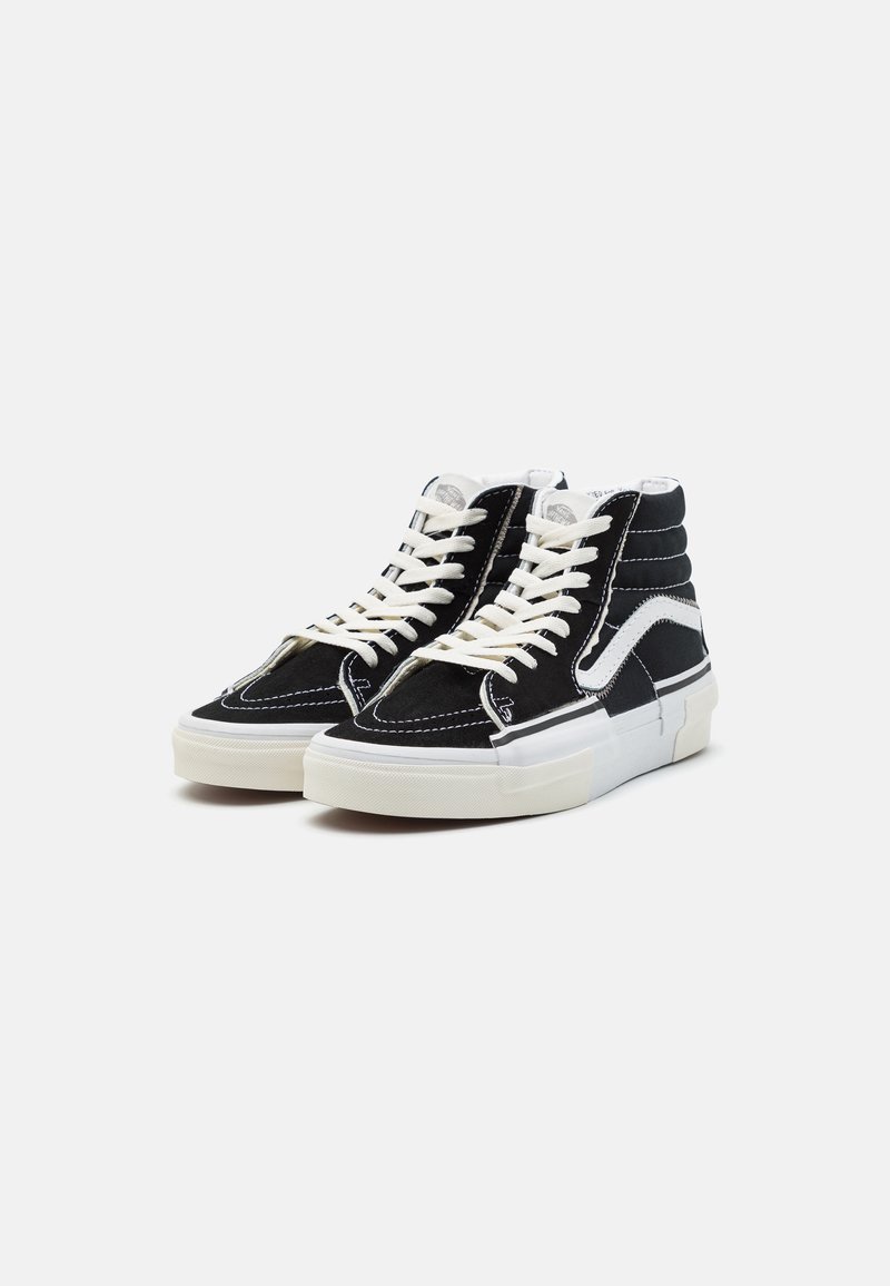 Sorte semskede høy-topp sneakers med hvite detaljer, med hvite snørebånd, sømmer og en teksturert gummisåle.