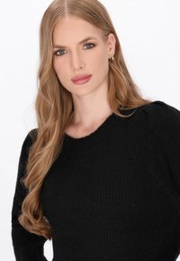 Zwarte geribde sweater met een ronde halslijn en een delicate pof-schouderontwerp. Zachte textuur verbetert het comfort en de stijl.