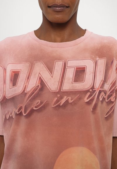 T-shirt graphique rose arborant un grand texte de logo, "DONDUN," avec un design défraîchi et un col rond, mettant en valeur une texture de tissu doux.