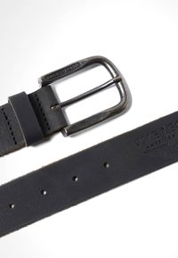 Ceinture en cuir noir avec boucle en métal gravée "PME LEGEND", présentant des boucles cousues et un logo en relief sur la sangle, avec cinq trous de réglage.