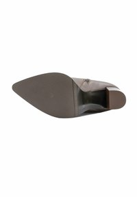 Bruin lederen schoen met een puntige neus en een lage blokhak. De zool is voorzien van een structuur met een rubberen afwerking voor grip.