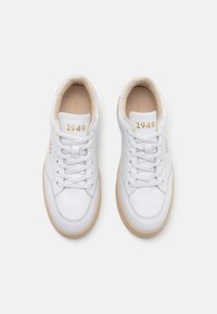Vita lädersneakers med krämfärgade detaljer, snörning och guldtexten "GANT 1949" på tungan. Ljusbrun gummisula.