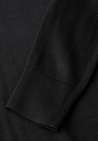 Tessuto di maglione nero con polsini a coste. Texture liscia, design aderente e maniche lunghe. Punti sottili sono visibili su tutto il materiale.