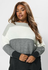 Sweter dziany w poziome paski w jasnoszarym, ciemnoszarym, białym i czarnym kolorze. Ma luźny krój oraz ściągacze przy rękawach i dolnym brzegu.