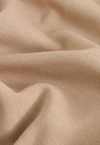Beige textured fabric with a fine weave, displaying soft, smooth contours and subtle variations in color under light.