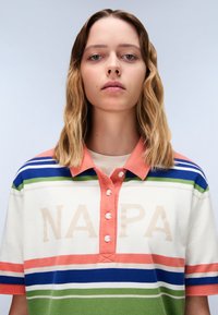 Gestreept polo shirt met een oranje kraag en knopen, voorzien van groene, blauwe en witte strepen. "NAPPA" gedrukt in zandkleur op de voorkant.