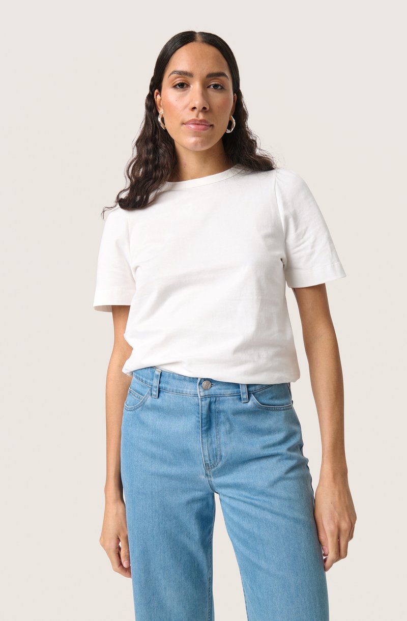 Witte katoenen t-shirt met korte mouwen, ronde halslijn, gecombineerd met lichtblauwe denim jeans. Naadloos ontwerp en zachte textuur.