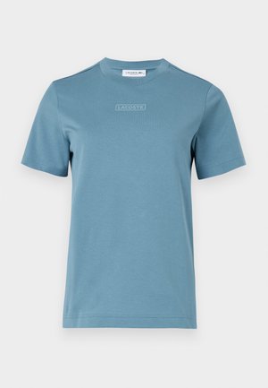Cotton crew-neck t-shirt in light blue, featuring a textured "LACOSTE" logo on the front. Short sleeves and a standard fit.
