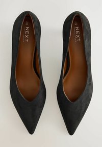 Svarta mocka pumps med spetsig tå och låg skärning, med en slät brun innersula och en elegant design. Lämpliga för formella tillfällen.
