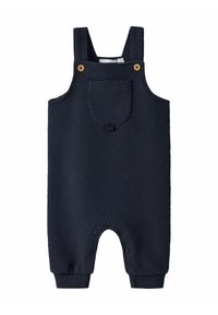 Combinaison bébé texturée bleu marine avec bretelles, poche avant avec rabat, boutons en bois et fermetures à pression au niveau de l'entrejambe et des jambes.