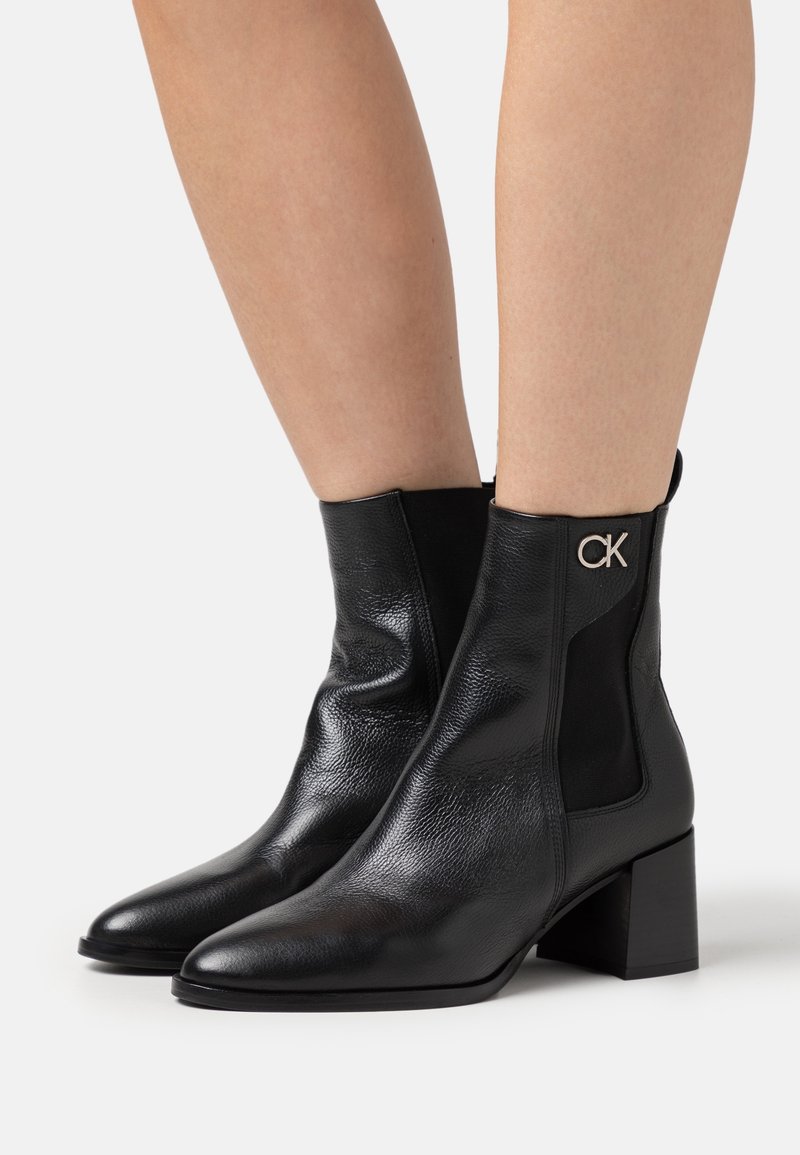 Bottines en cuir noir avec une finition texturée, un talon bloc et des panneaux latéraux élastiques. Présentent un logo CK sur le côté extérieur.