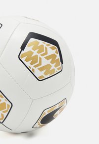Pallone da calcio bianco con motivi esagonali neri e dorati. Presenta cuciture visibili e una superficie liscia e lucida.