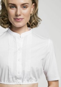 Weißes, kurzes Shirt mit kurzen Ärmeln, das einen Stehkragen, eine frontale Knopfverschluss und vertikale Falten entlang der Knopfleiste aufweist. Glatte Textur.