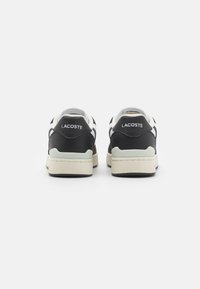 Sneaker bianche e nere con pelle liscia, suole in gomma e dettagli testurizzati. Presentano il nome del marchio sul tallone e un design classico.