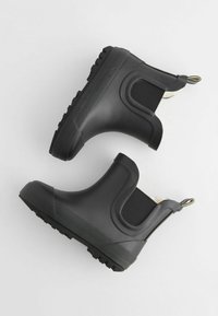 Bottes noires en caoutchouc à chevilles avec panneaux latéraux élastiques, semelle à grip texturé et tirant. Surface lisse avec finition mates.
