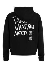 Zwarte hoodie met grote witte tekst op de achterkant: "NEEM WAT JE NODIG HEBT." met aanvullende zinnen hieronder in kleinere letters.