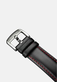 Schwarzes Lederarmband mit roter Naht, ausgestattet mit einer rechteckigen silbernen Metallschnalle, die mit "Carlo Calucci" graviert ist. Glatte Textur.