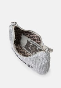 Ezüst flitteres clutch táska cipzárral, belül fekete logó mintázattal és sima felülettel. Kompakt, stílusos dizájn a szükséges dolgok hordozásához.