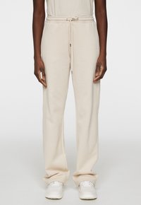 Beige Jogginghose aus weichem Stoff, mit einem elastischen Bund mit Kordelzug und Seitentaschen, in lockerer Passform.