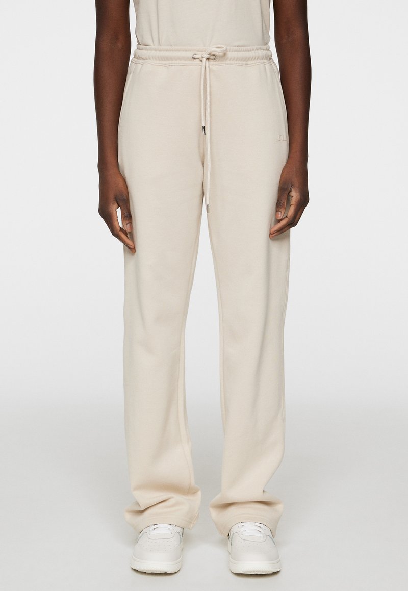 Beige Jogginghose aus weichem Stoff, mit einem elastischen Bund mit Kordelzug und Seitentaschen, in lockerer Passform.
